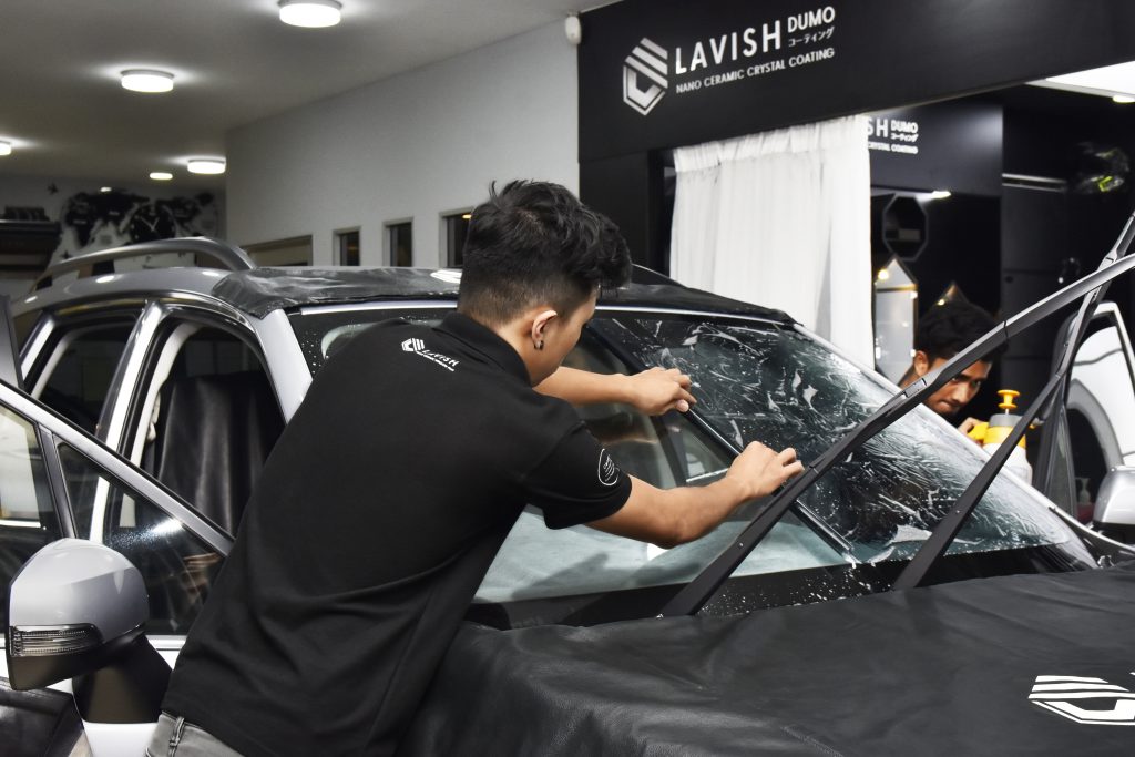 Lavish Window Film's staff is applying window tint to a car.